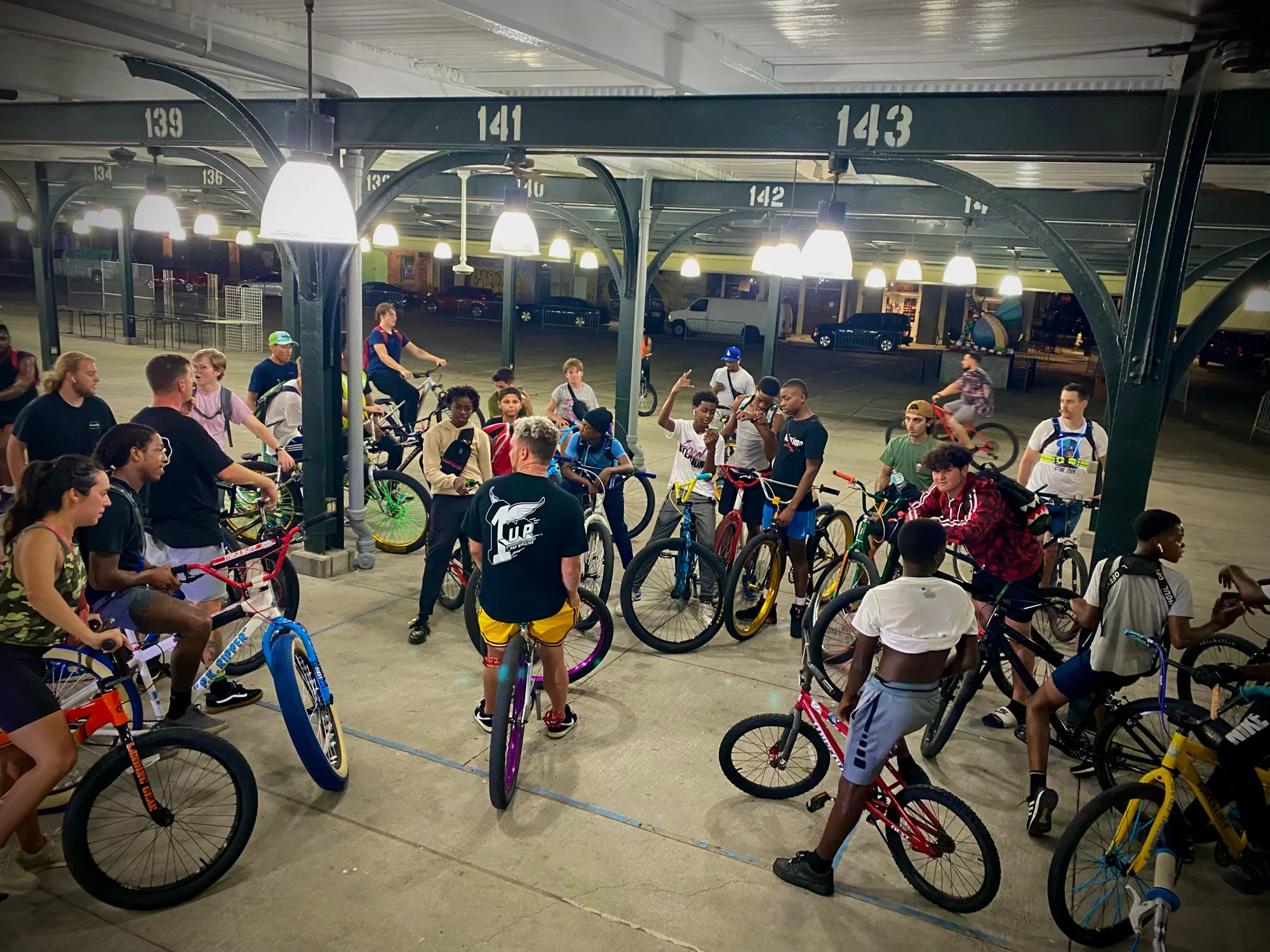 Night ride-out under a pavilion with a rider wearing a 1Up Bike Life shirt